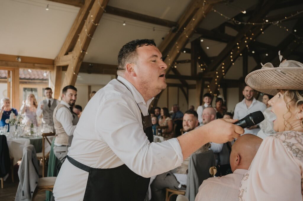 Singing waiter handing the microphone to a guest at a wedding