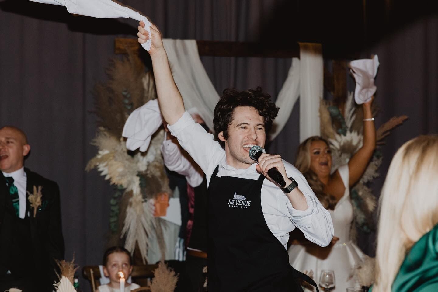 Singing waiter waving a napkin as guests dance at a wedding