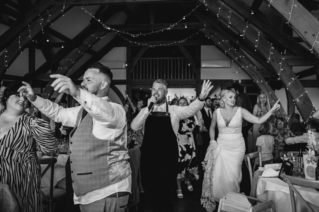 Black and white photo of singing waiters dancing with the bride
