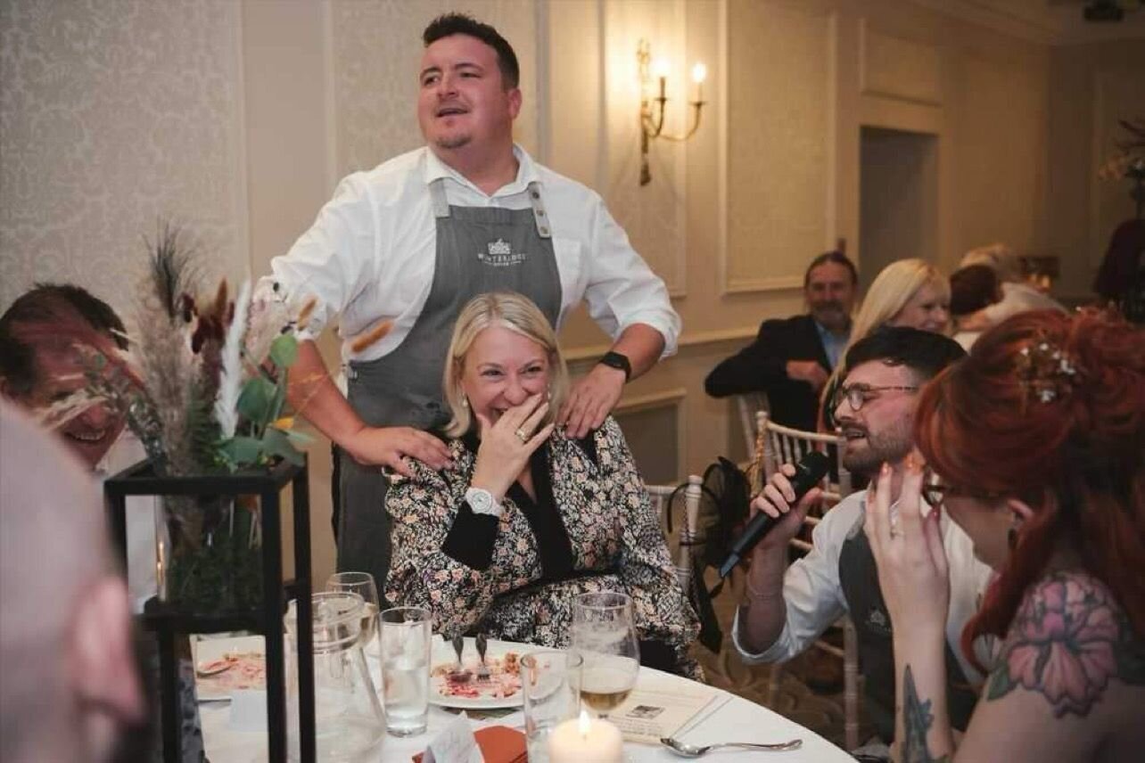 Singing waiter surprising a guest at her seat