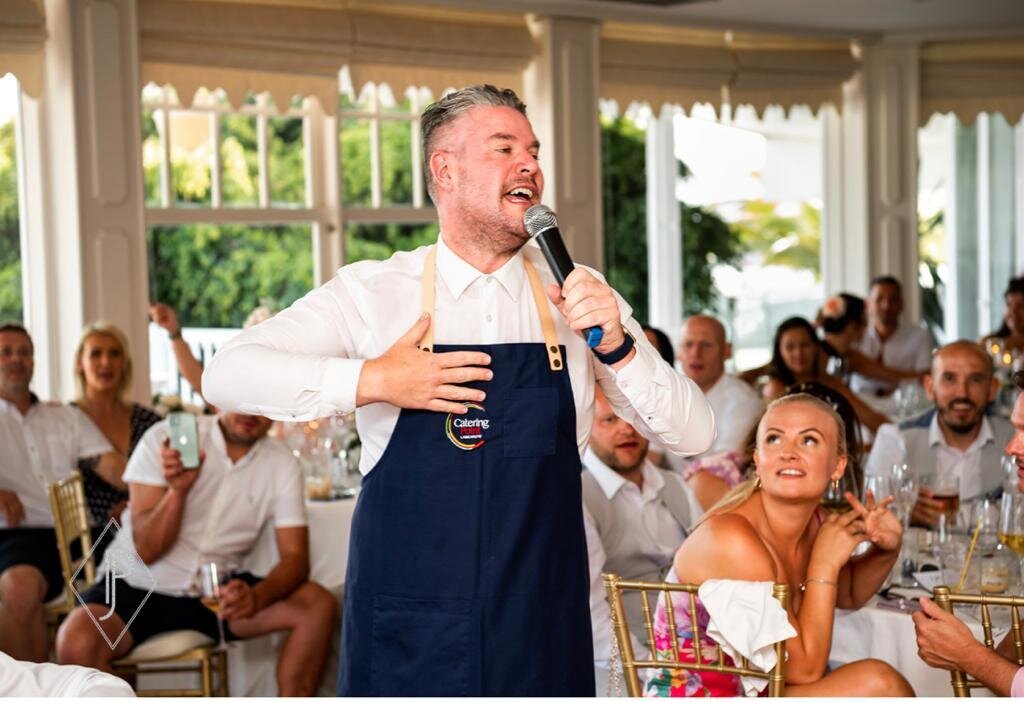 Singing waiter in an apron performing to wedding guests
