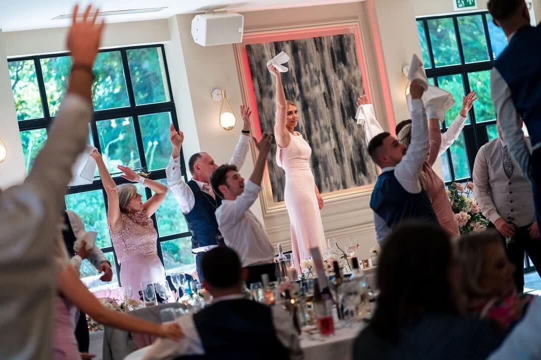 Wedding guests with arms raised during a singing waiters performance