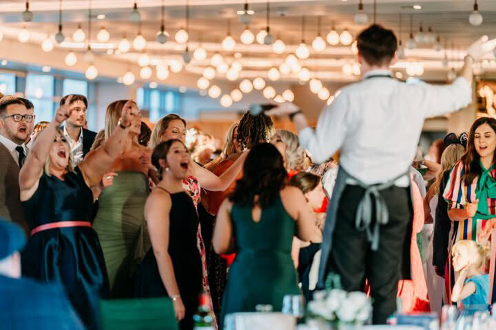 Wedding guests dancing and cheering as a singing waiter performs