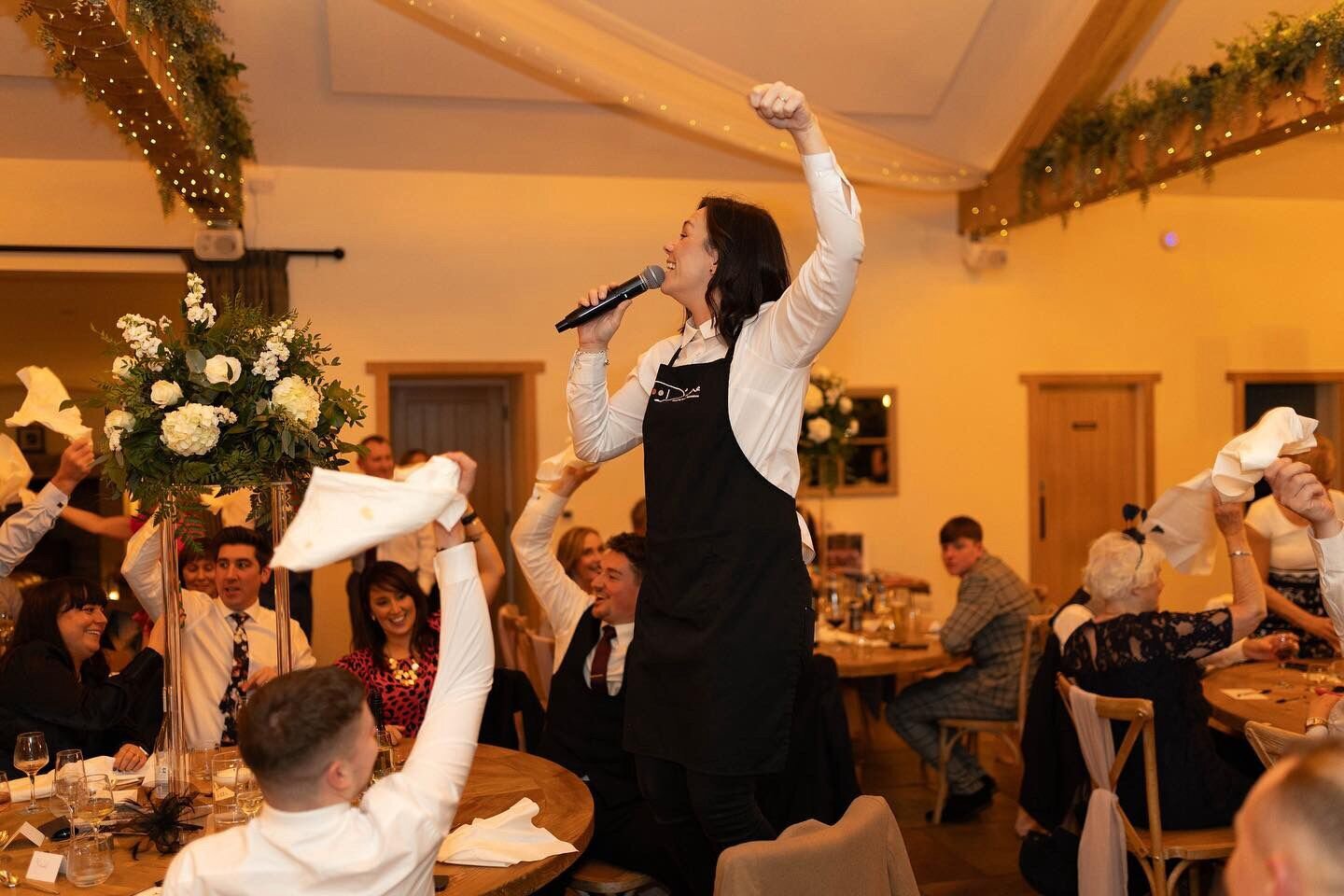 Singing waiter standing on a chair as guests wave napkins