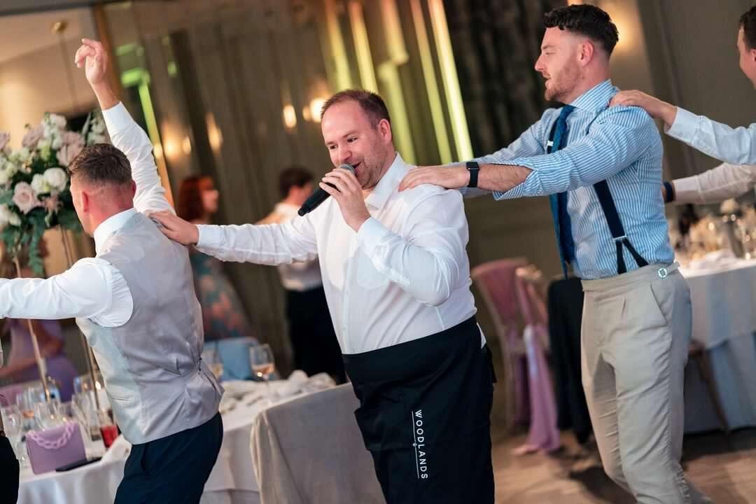 Singing waiters leading guests in a sing-along at a wedding