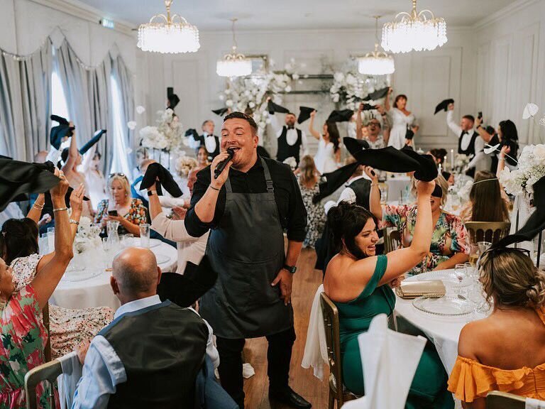 Guests waving napkins as a singing waiter performs in a ballroom