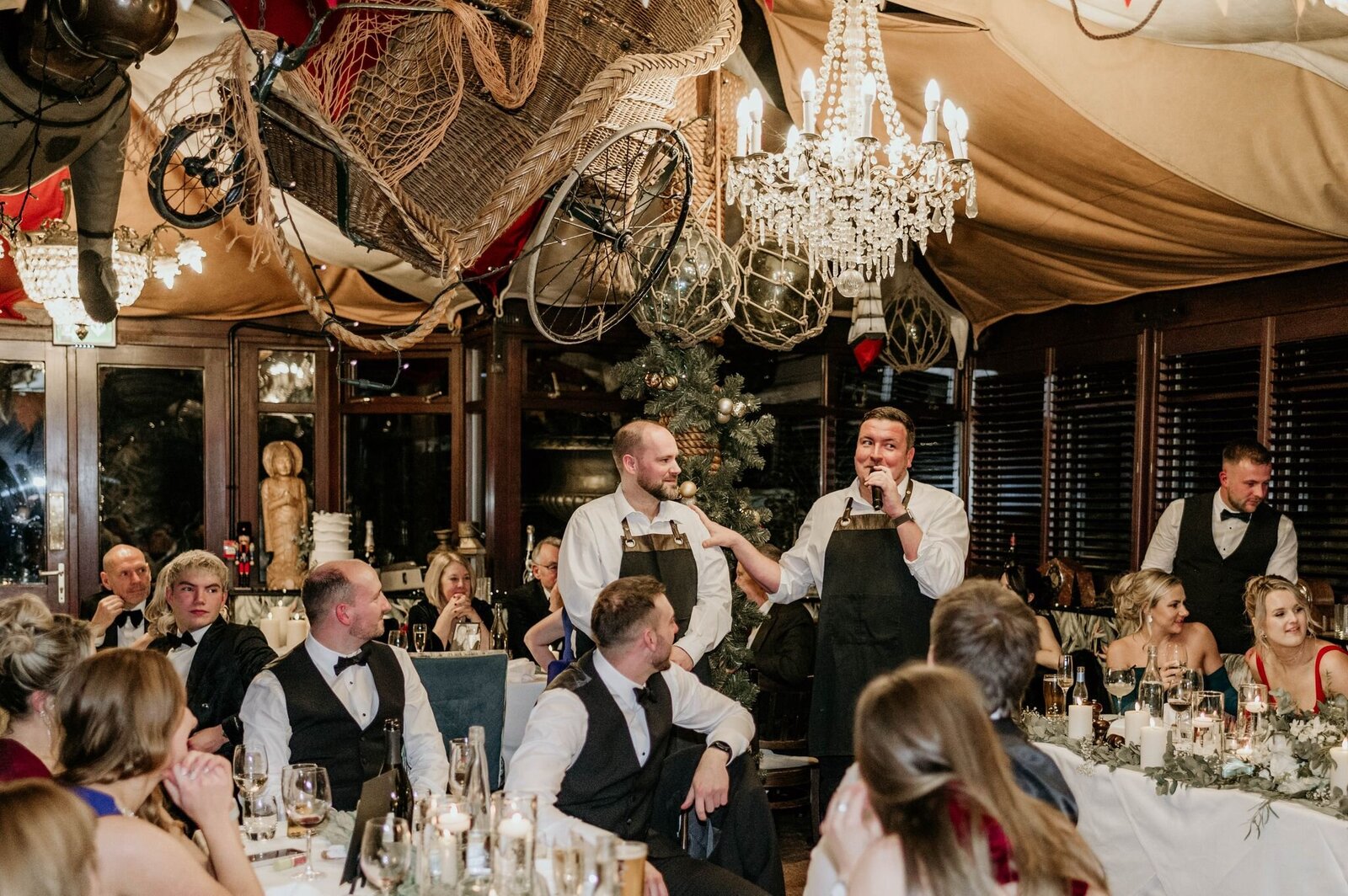 Singing waiters performing in a chandelier-lit wedding venue