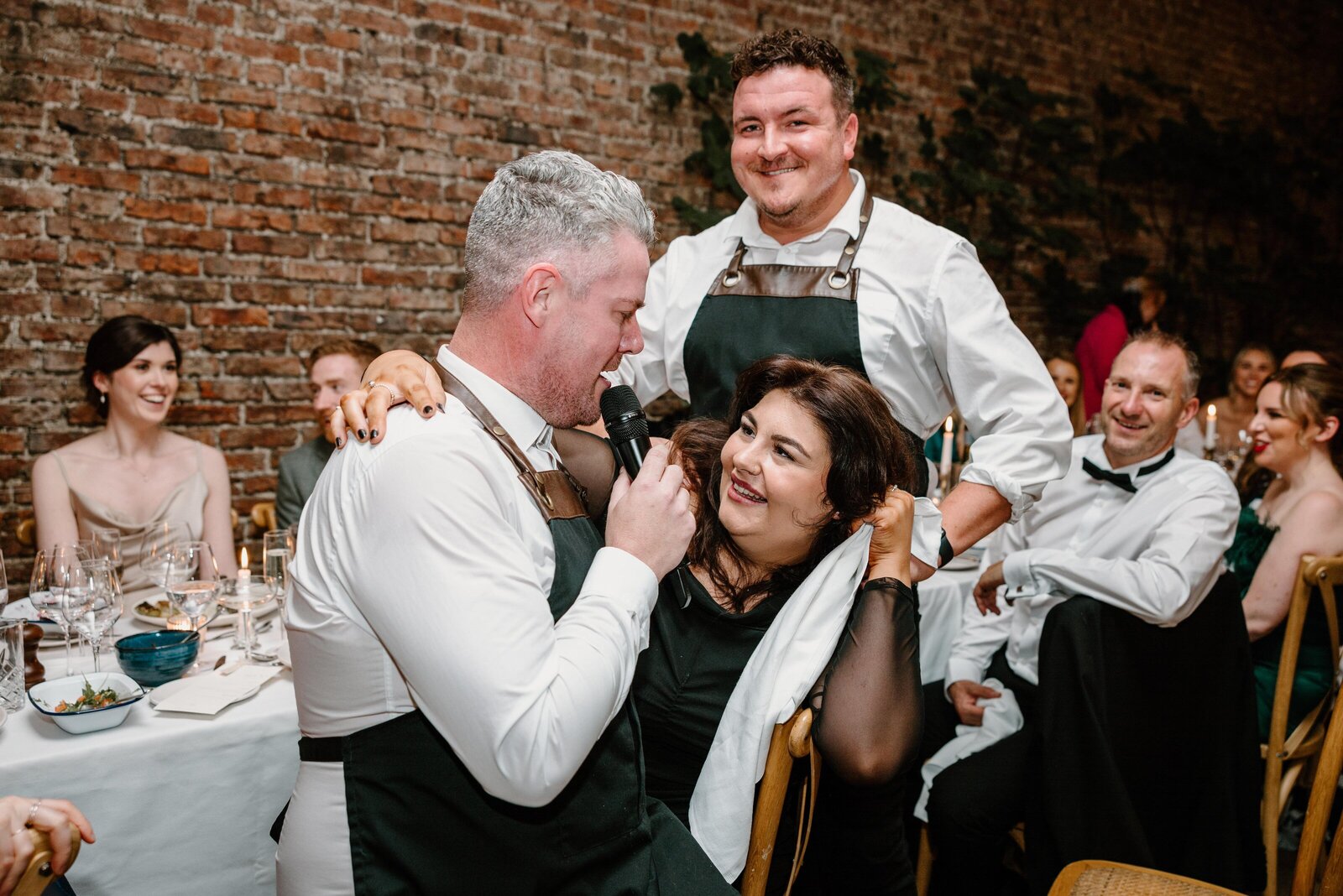 Two singing waiters serenading a guest at her table