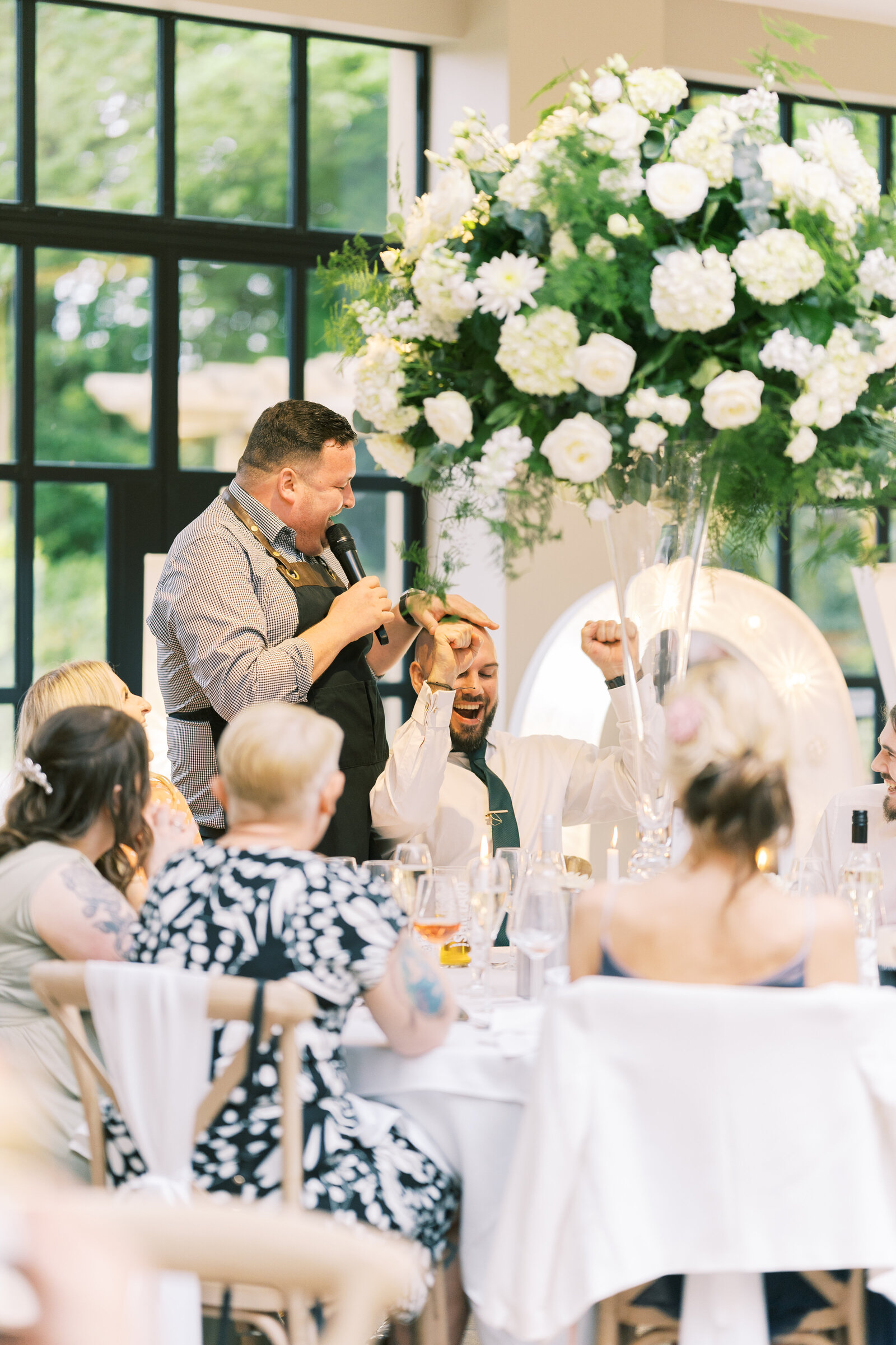 Singing waiter performing beside a floral centrepiece at a wedding