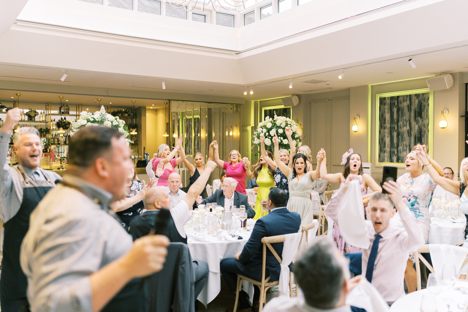 Guests with arms raised as the singing waiters perform in an orangery