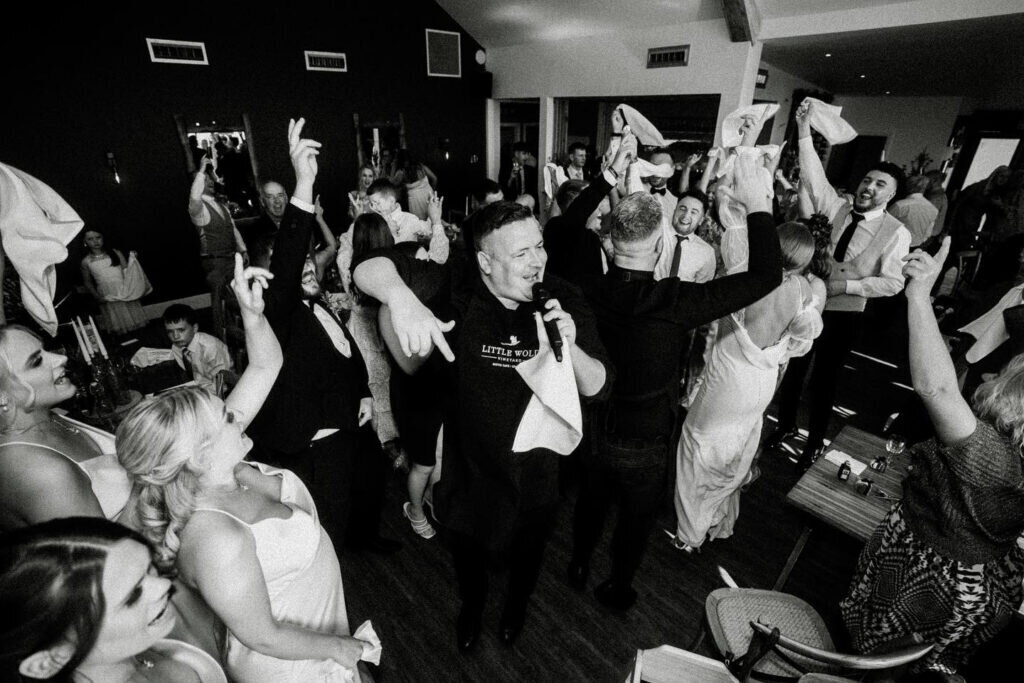 Party guests on their feet waving napkins during a singing waiters show