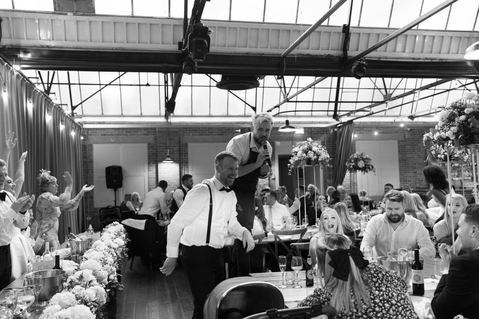 Singing waiters performing in a large wedding venue, black and white