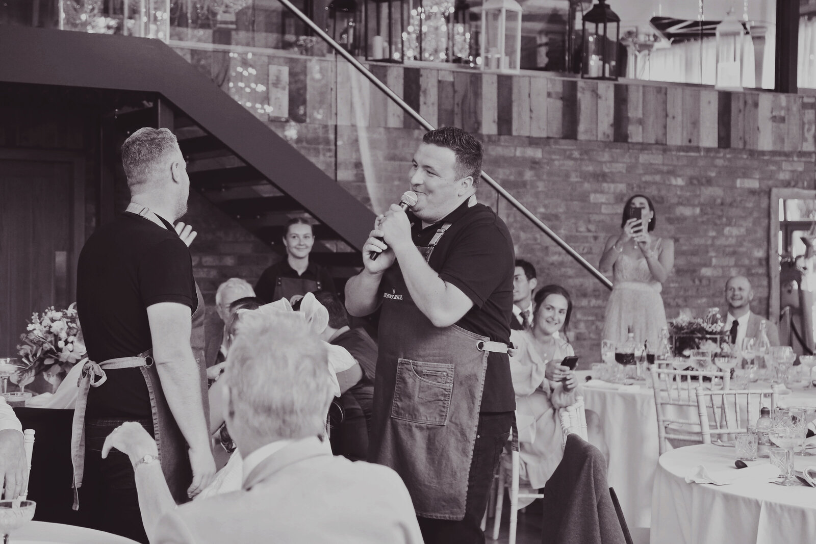 Singing waiters performing to wedding guests, black and white