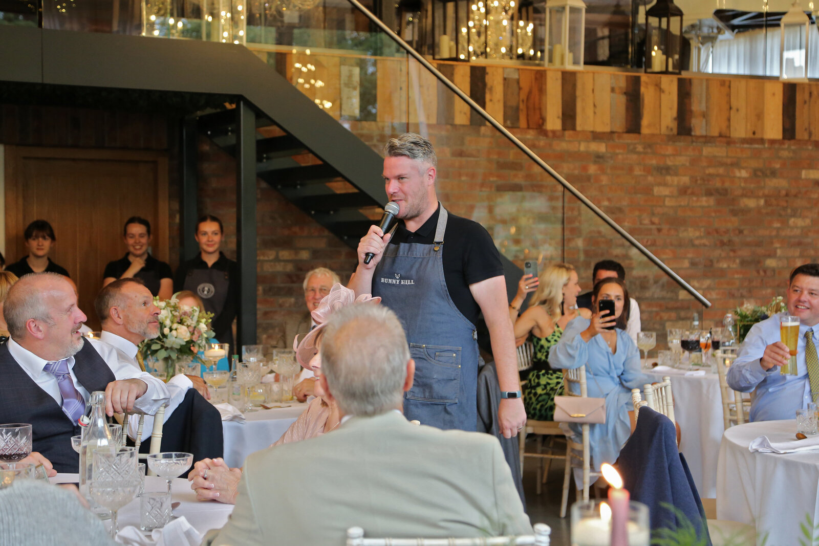 Singing waiter in a denim apron performing to wedding guests