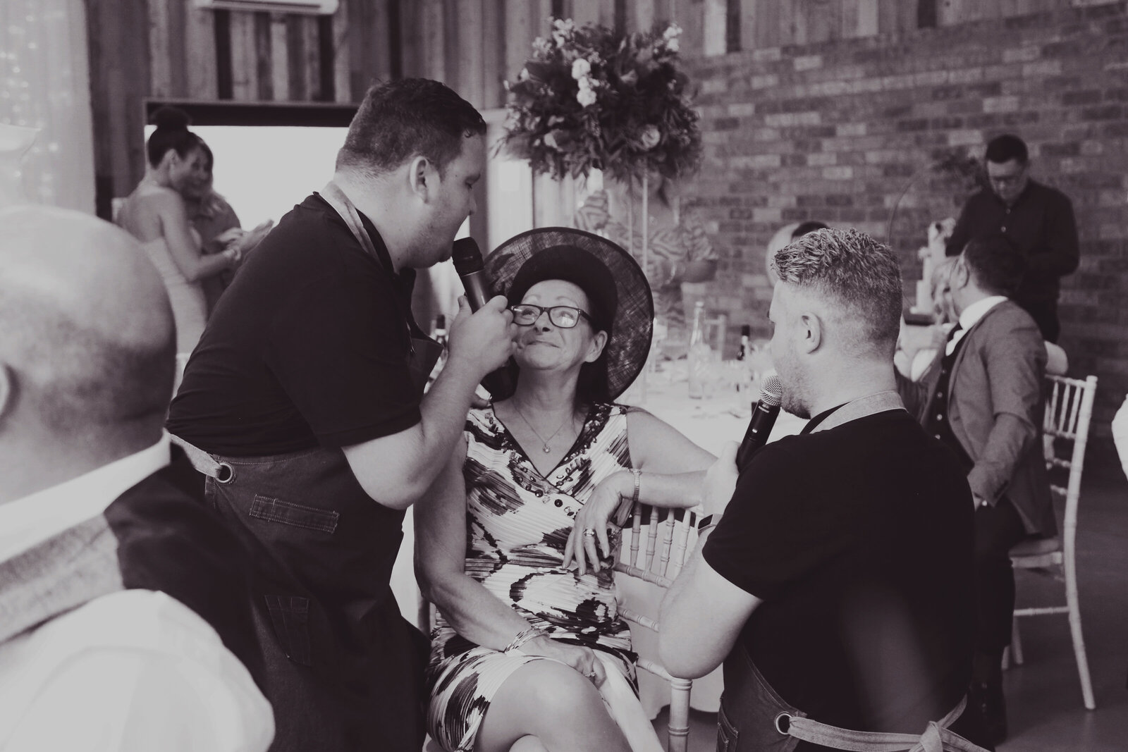 Singing waiter serenading a guest in a hat, black and white