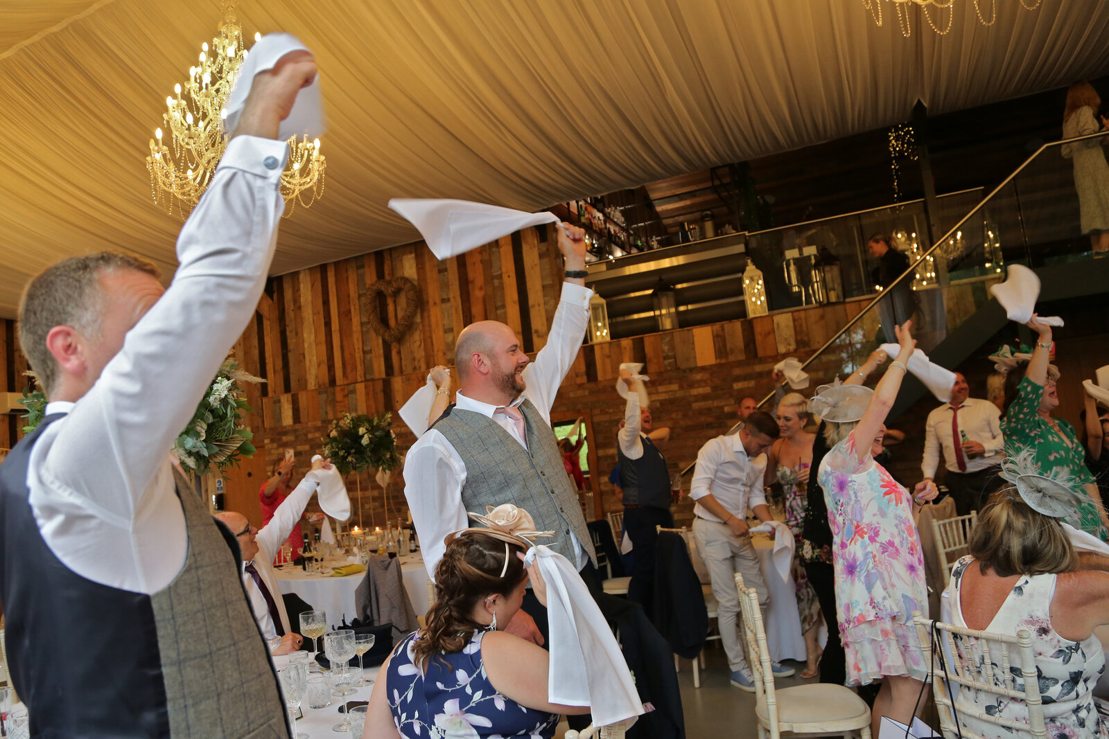 Guests waving napkins at a wedding with chandeliers