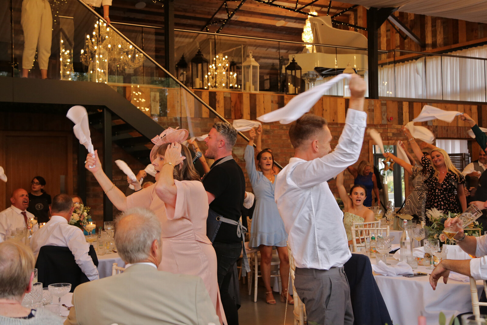 Guests waving napkins in a rustic barn wedding reception