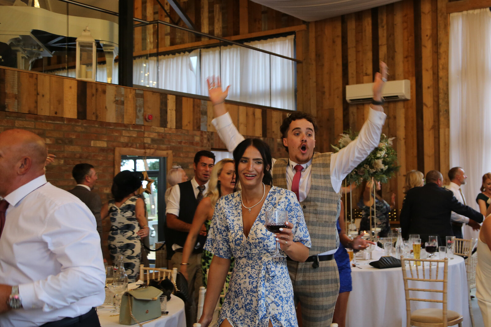 Guests dancing with a singing waiter at a barn wedding