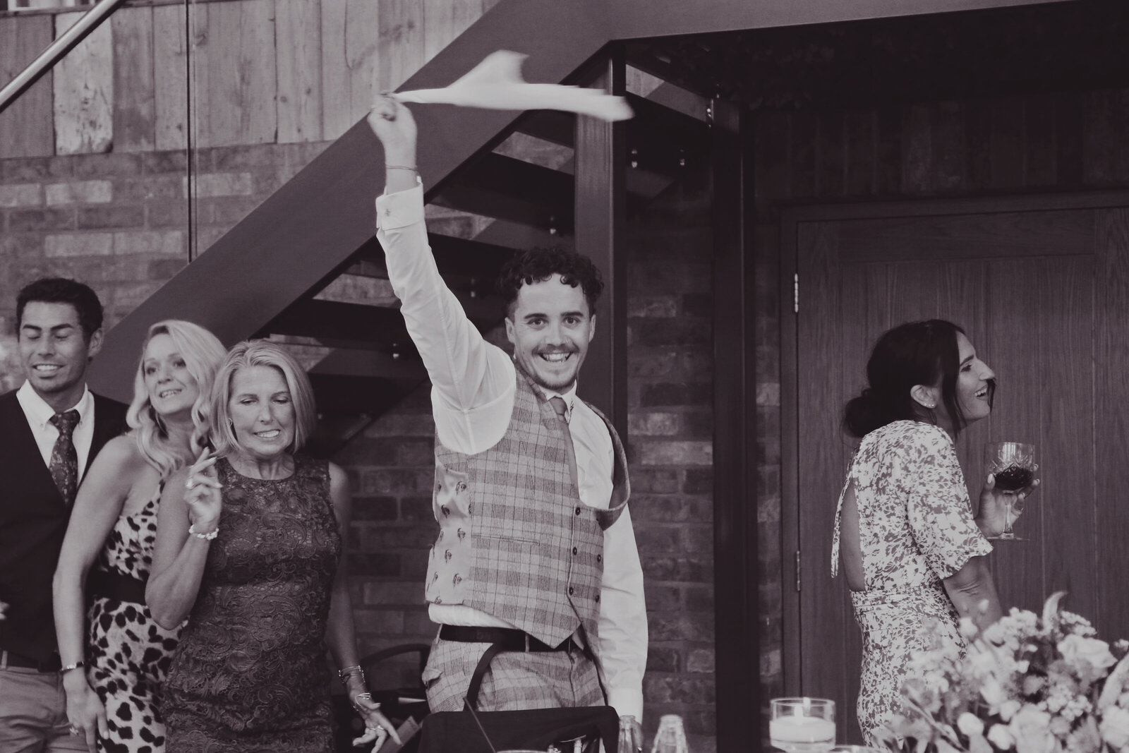 Guest in a kilt waving a napkin with the singing waiters, black and white