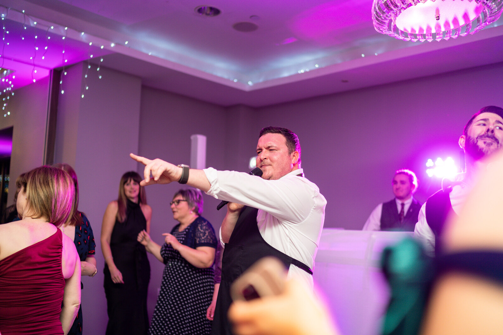 Singing waiter performing under purple party lighting