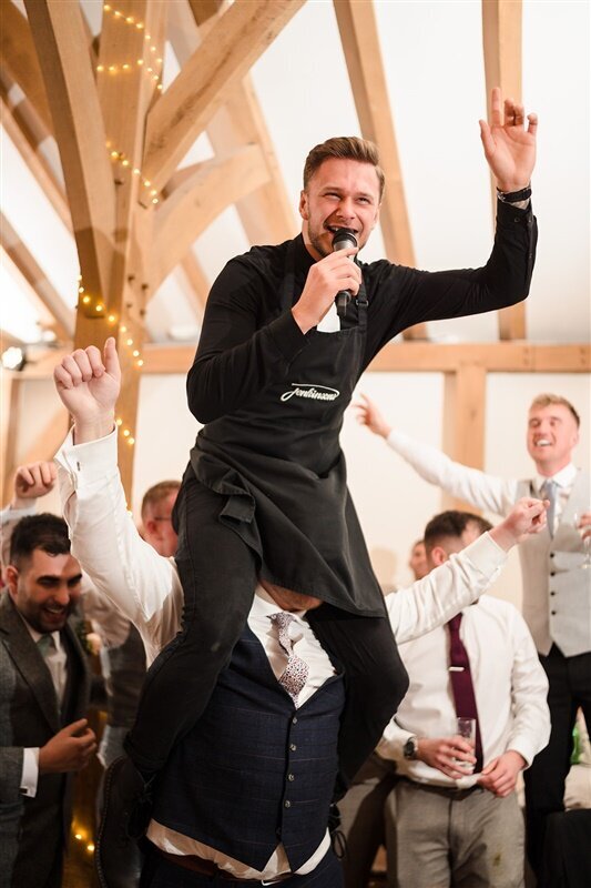 Singing waiter standing on a chair performing to a barn wedding
