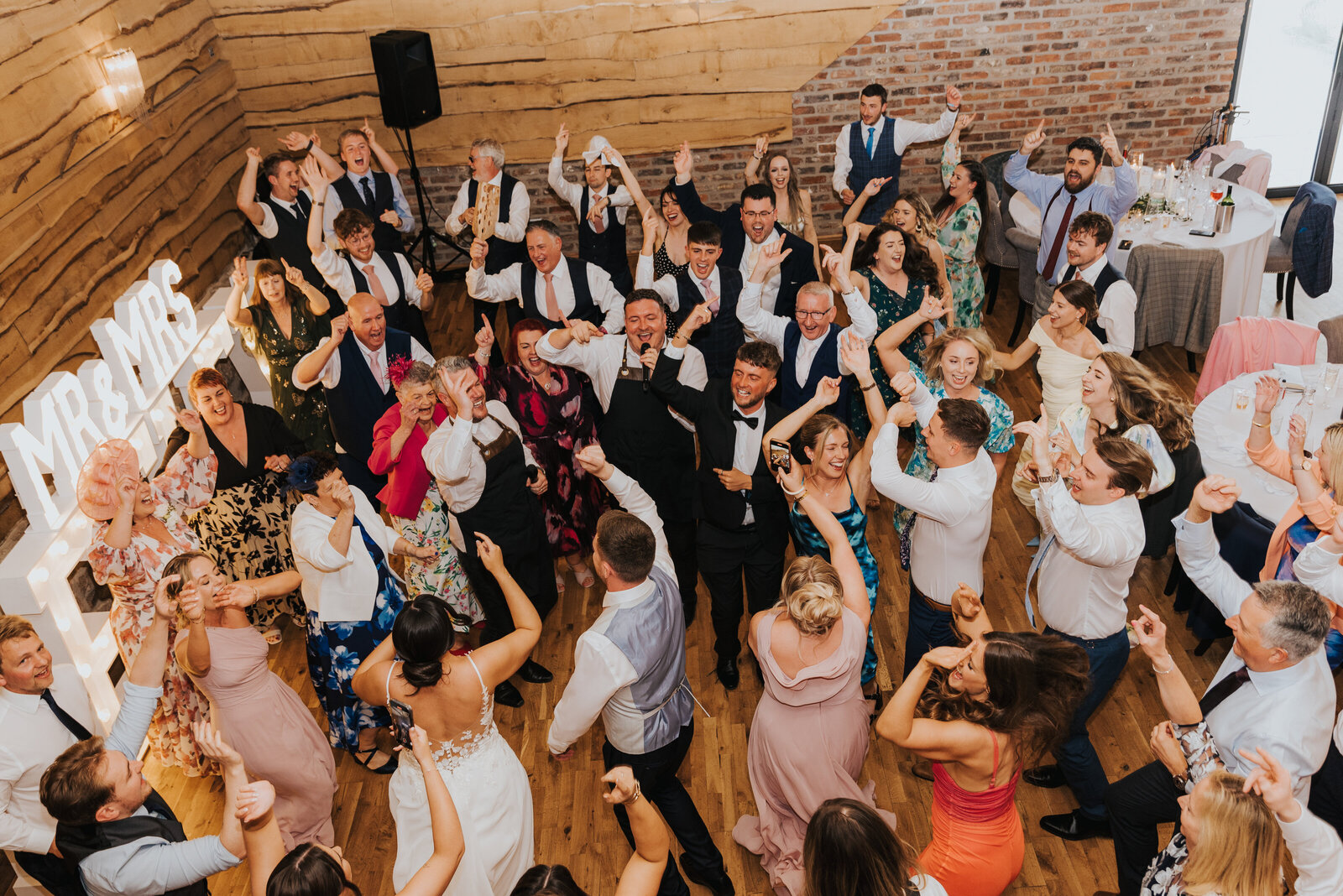 Packed dance floor of wedding guests with the singing waiters