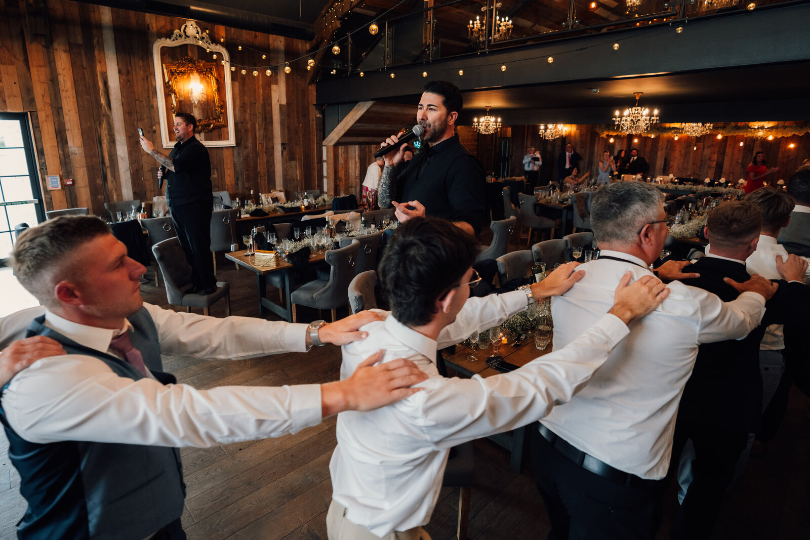 Singing waiters and guests linking arms at an evening reception
