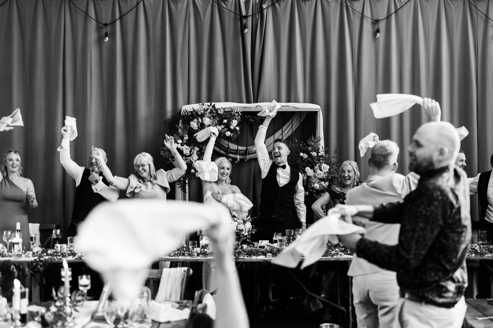 Guests waving napkins at a wedding, black and white