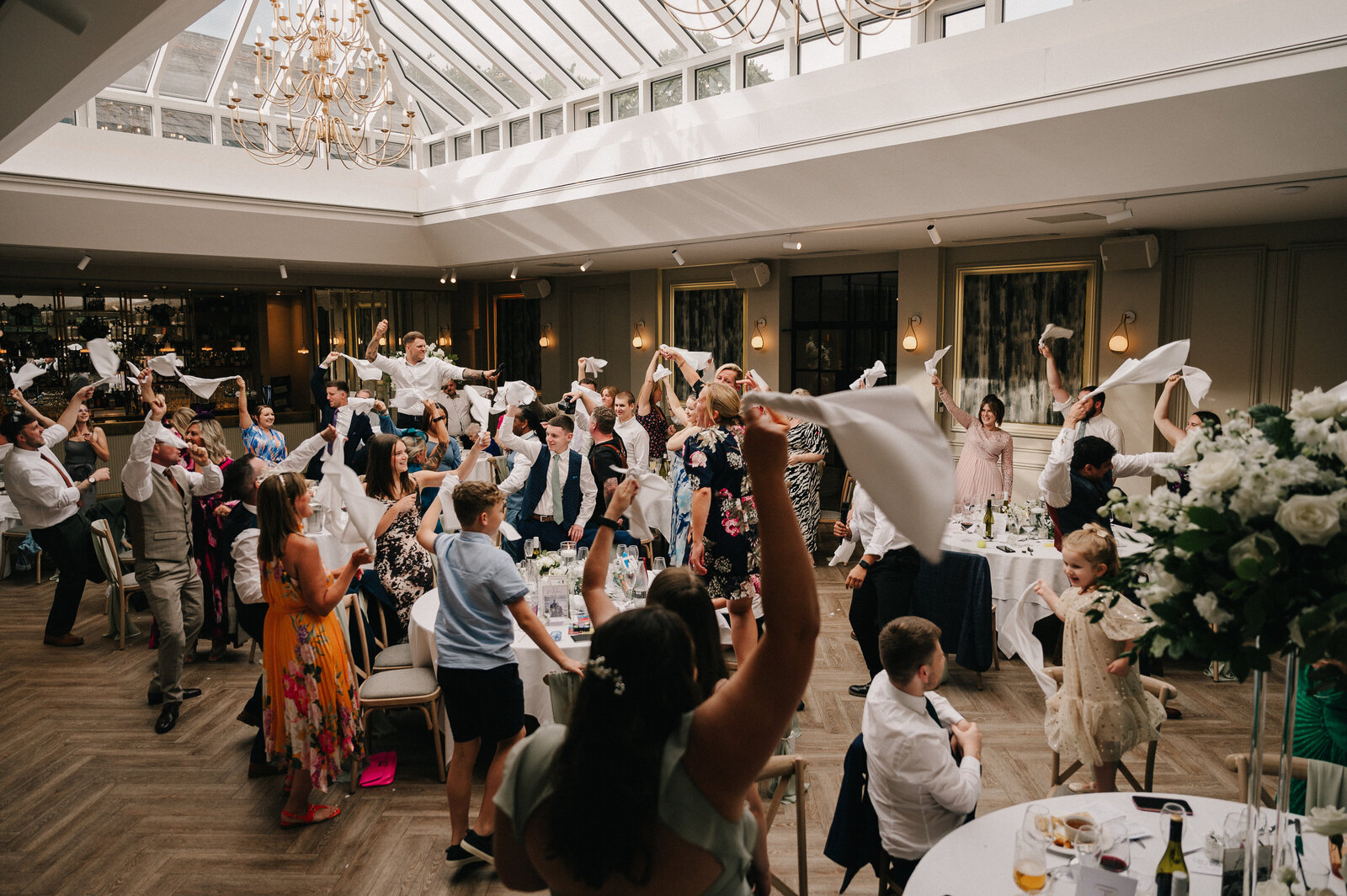 Wedding guests on their feet waving napkins during a singing waiters performance
