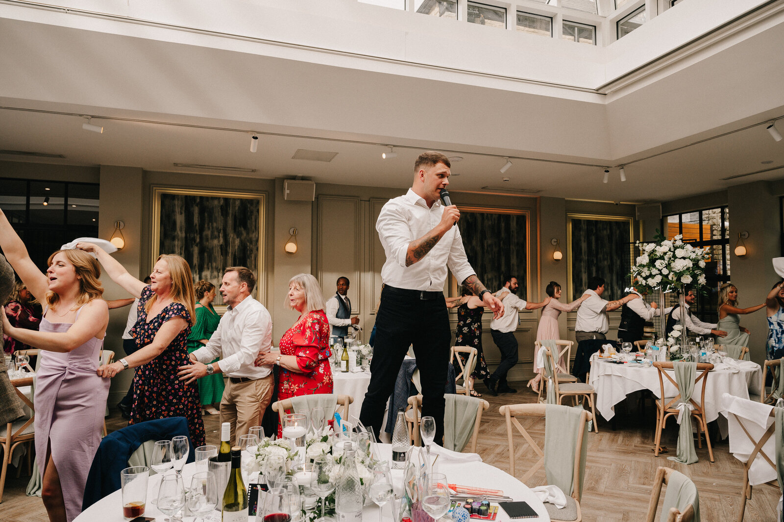 Singing waiter standing on a chair performing to wedding guests