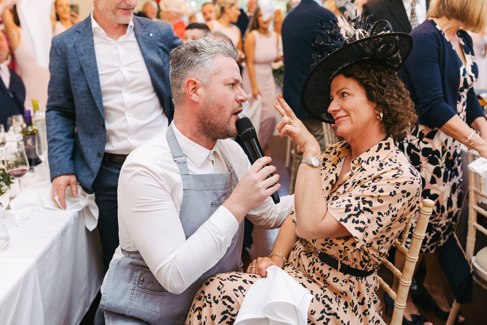 Singing waiter kneeling to serenade a guest at a wedding