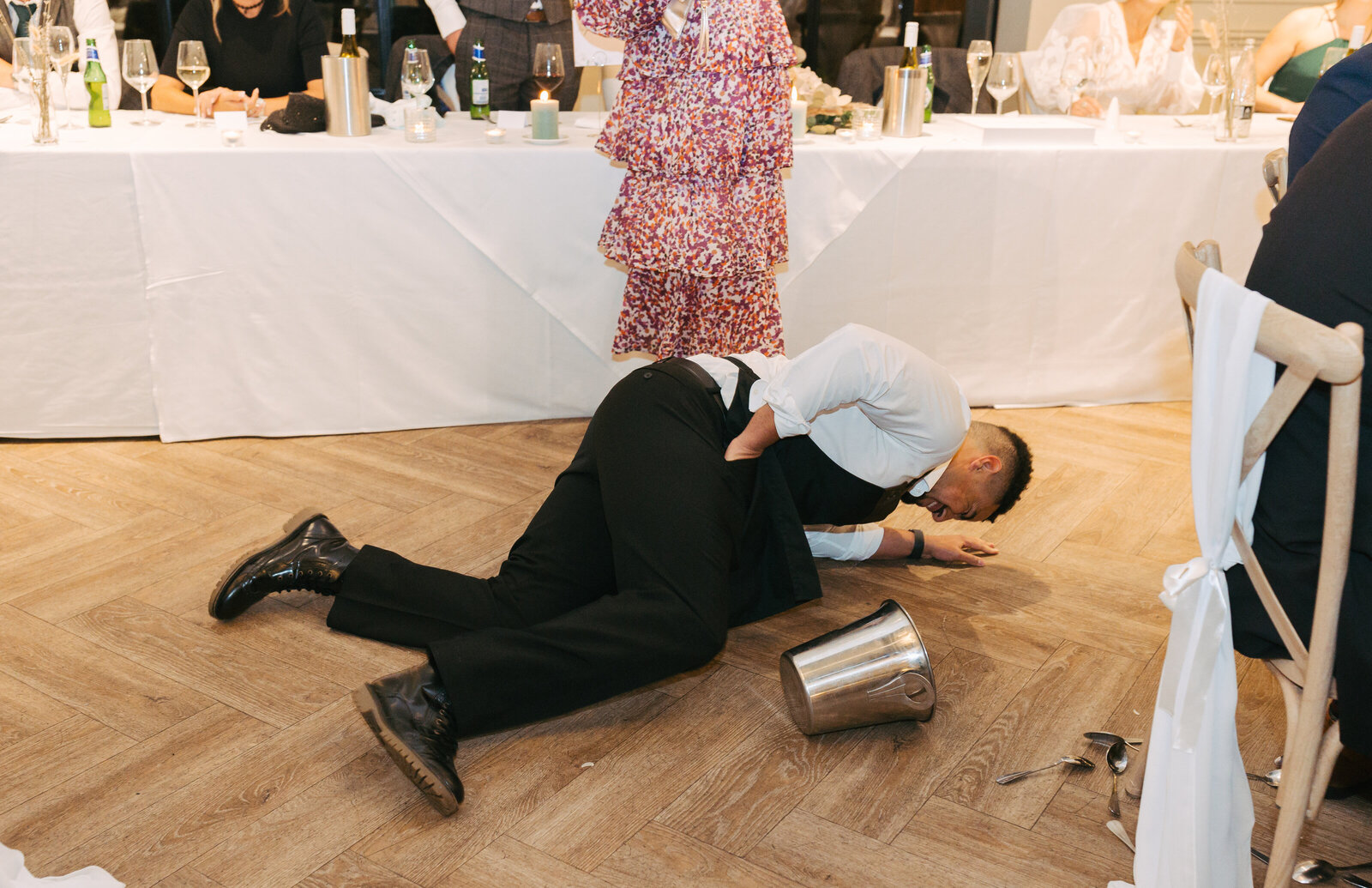Singing waiter lying on the floor mid-song as wedding guests watch