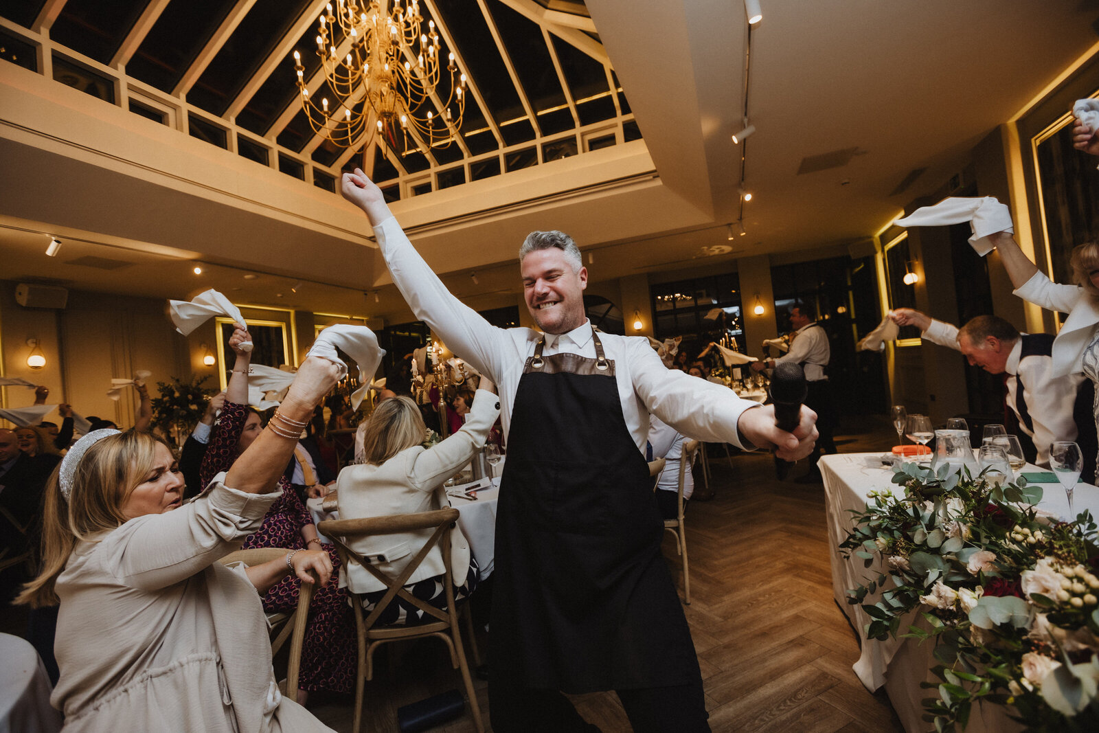 Singing waiter leading a napkin-waving crowd at a wedding reception