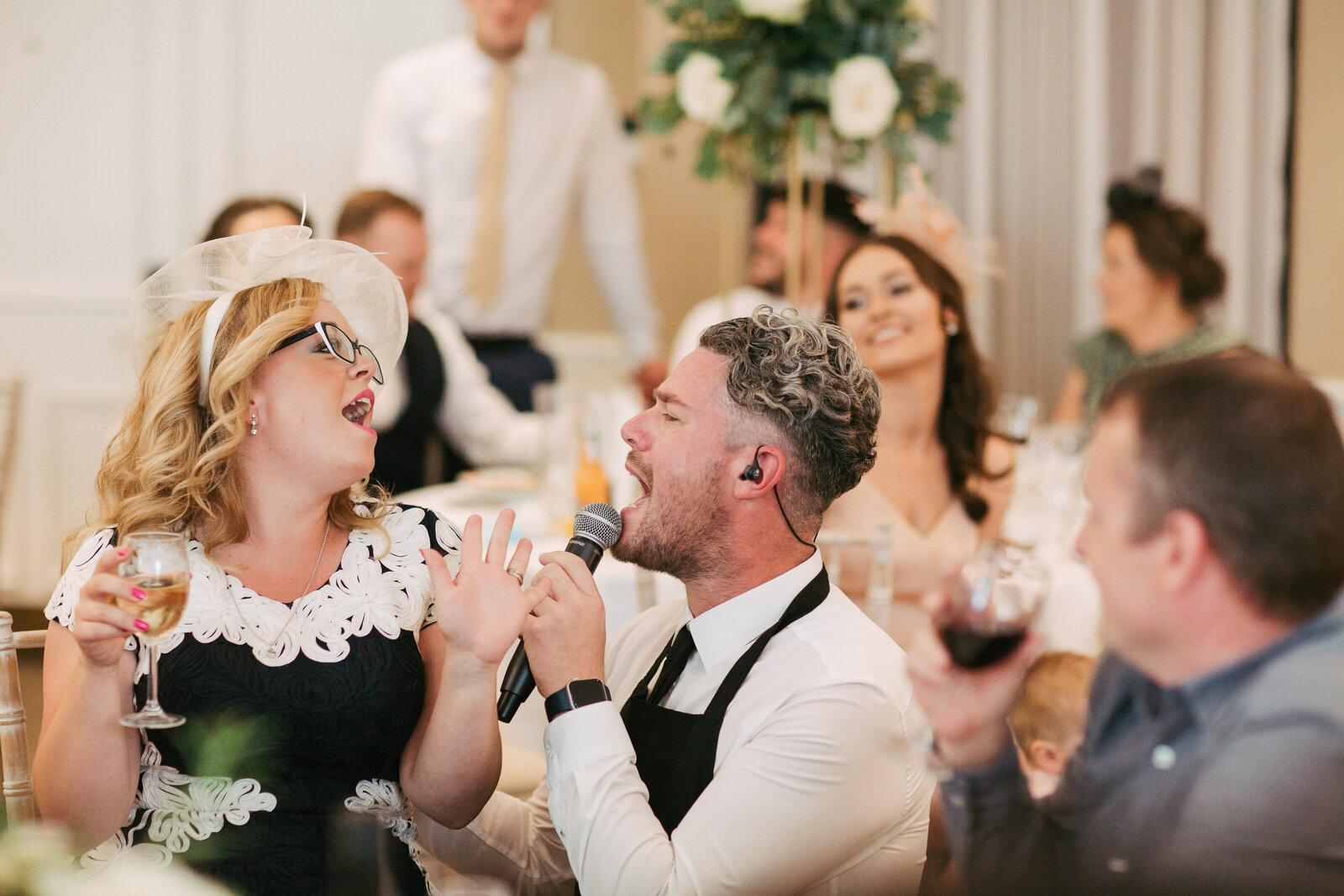 Singing waiter serenading a laughing guest at her table